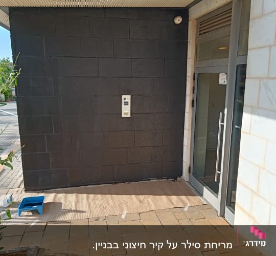 מגש צבע וכפפות על רצפה ליד קיר שחור